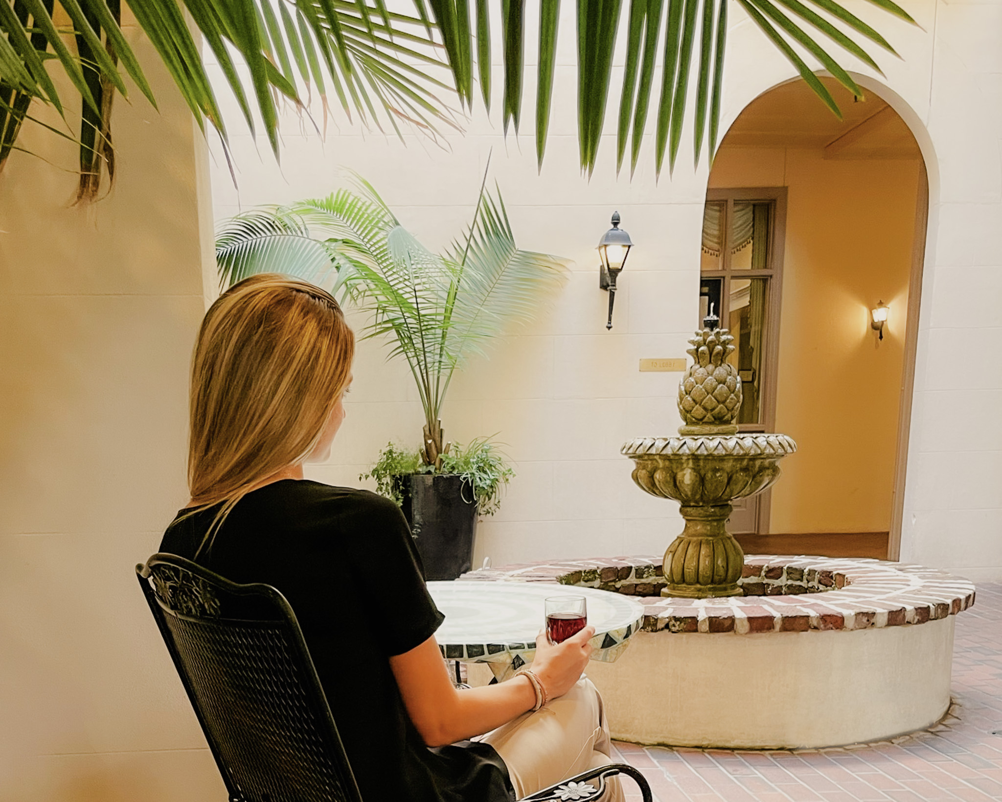 Guest with a glass of wine in the Pineapple Courtyard in Kings Courtyard Inn